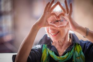 Cute senior old woman making a heart shape with her hands